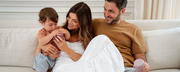 Couple sitting on couch with toddler playing with a jar - WeNatal prenatals